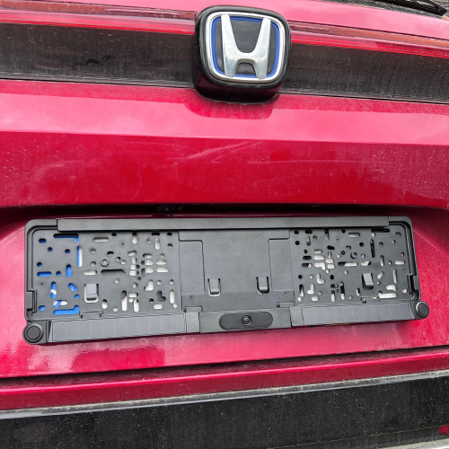 Rámik ŠPZ s integrovanou kamerou 170° namontovaný na zadnej časti červeného auta Honda