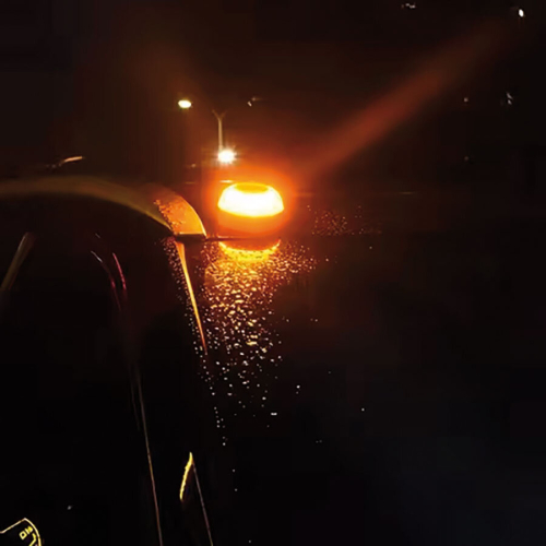 Výstražné LED svetlo V16 prichytené magnetom na streche auta v noci, oranžové výstražné svietenie.