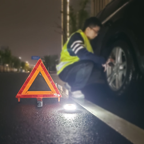 Výstražné LED svetlo V16 na ceste vedľa výstražného trojuholníka, biely svetelný režim osvetľujúci pracovný priestor.